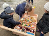 Die Handwerker schenken den Kindern einen selbstgebauten Holzwagen mit Süßigkeiten